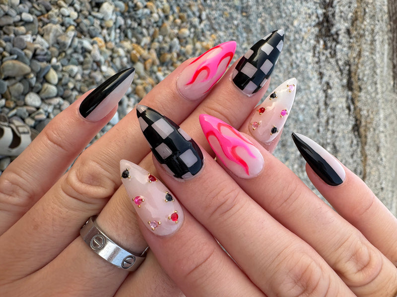 Close-up of a hand with stylized nail art on a pebbly surface